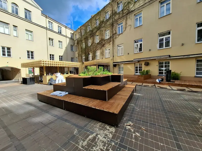 Bendras kiemo vaizdas: pakopinės sėdimos vietos, kioskai su grotelėmis ir terasos
