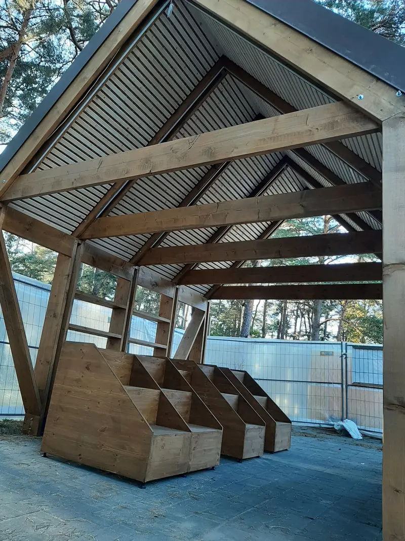 Atviro paviljono vidus su laiptuotomis medinėmis dėžėmis, lentynomis ir lentjuosčių lubomis
