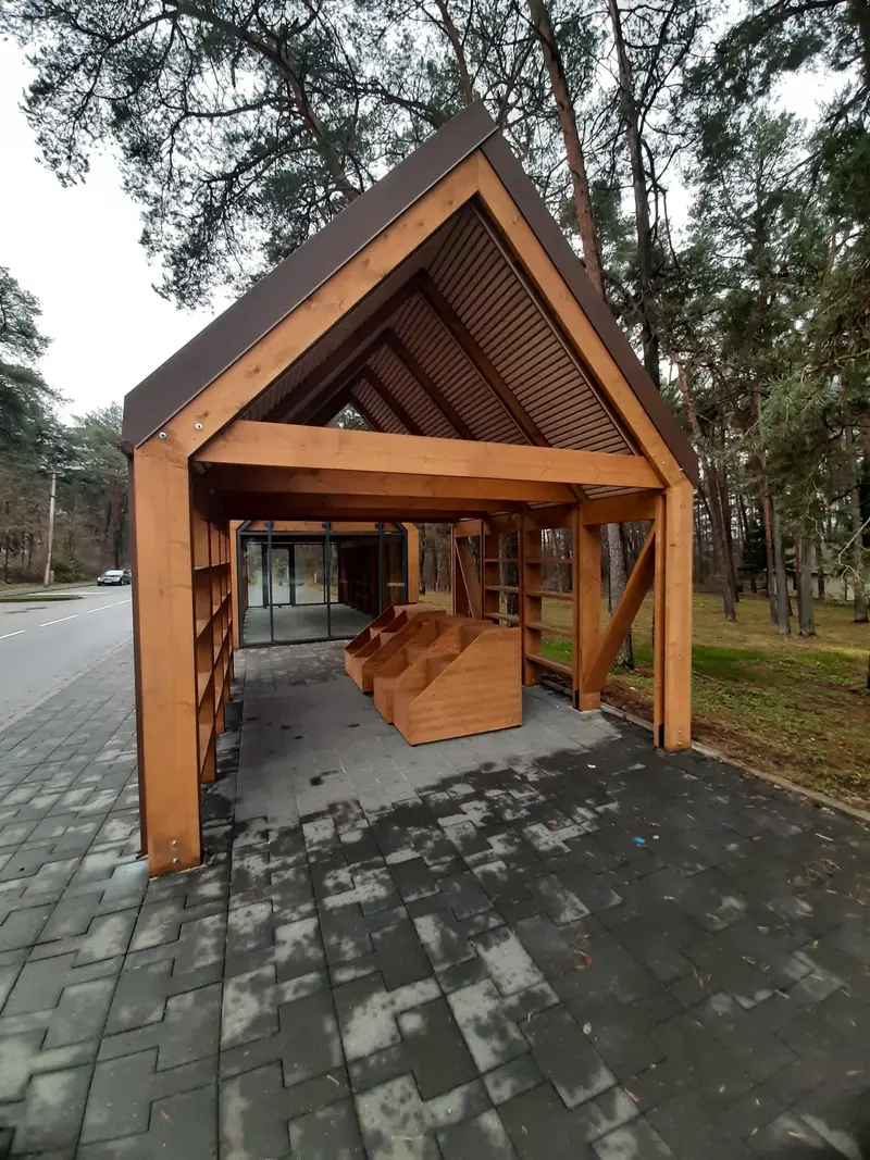 Žvilgsnis pro atviro paviljono galą į vidų, matyti dėžės, lentynos ir įstiklintas paviljonas