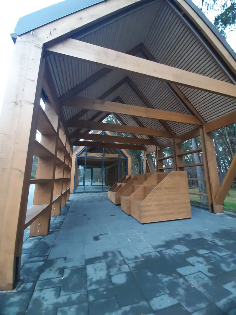 Atviro paviljono vidus su sijomis, lentjuosčių lubomis ir vaizdu į įstiklinto paviljono galą